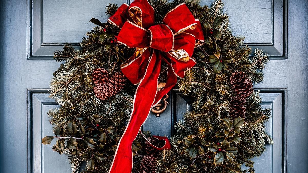 Vibrant Christmas wreath with large red bow trimmed in gold hang