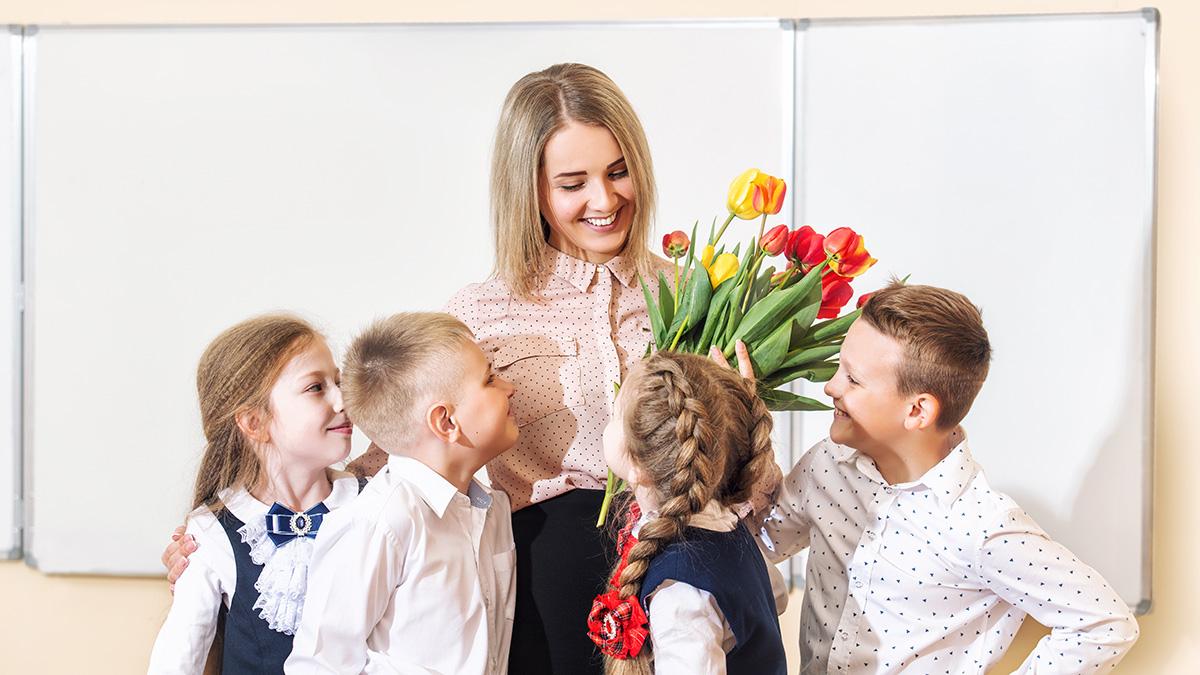 Beautiful children students together in class at school give flowers to their best woman teacher