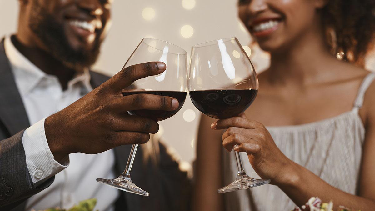 Close up of cheerful african american couple toasting with red wine, celebrating anniversary