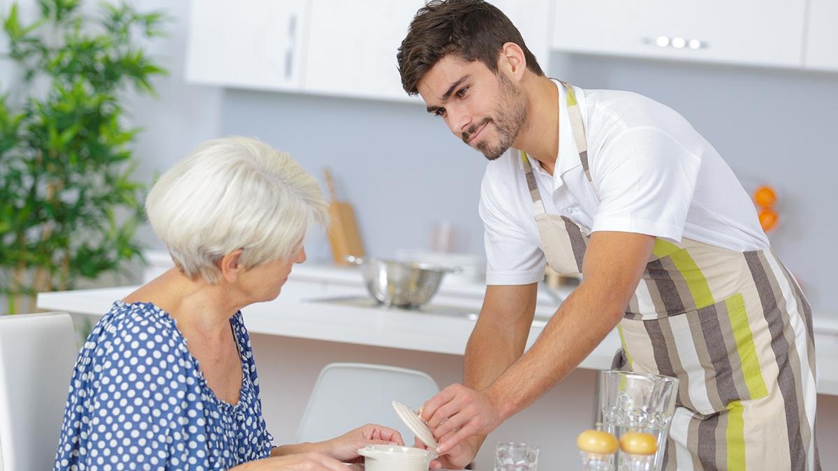 carer serving lunch to senior woman