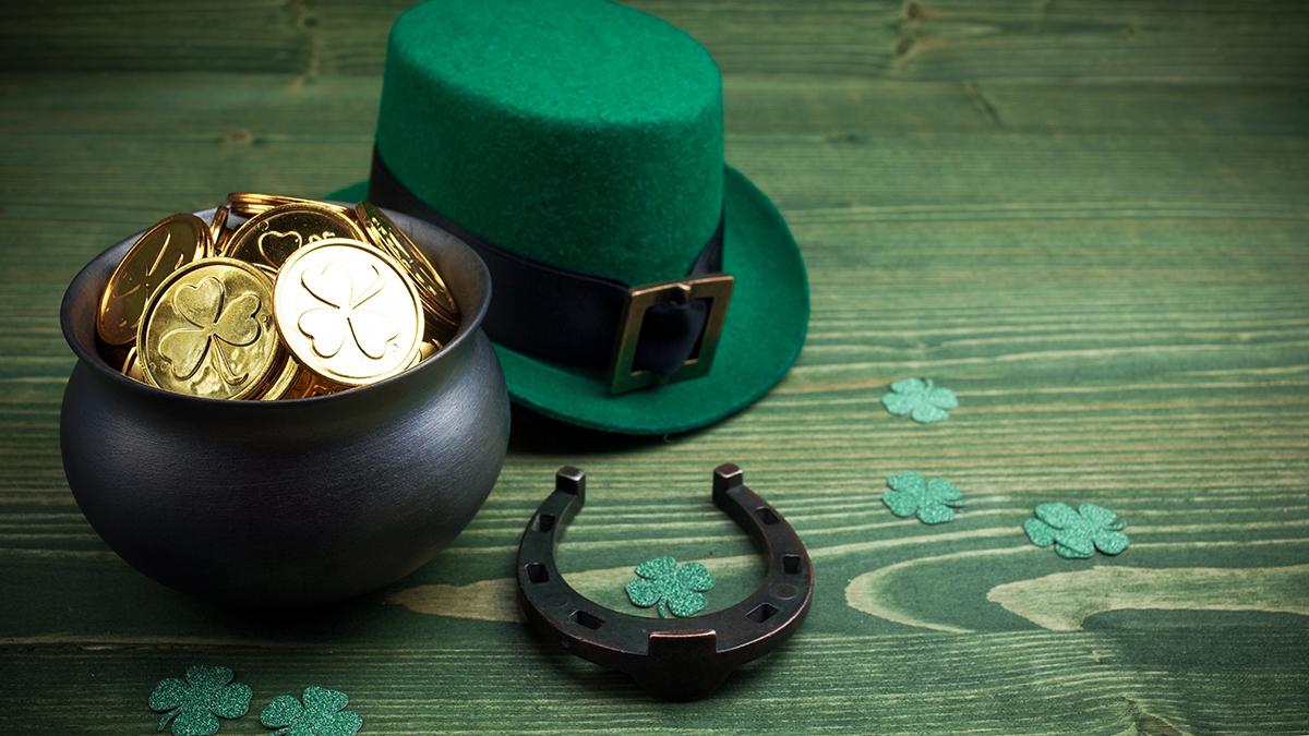 Happy St Patricks Day leprechaun hat with gold coins and lucky charms on vintage style green wood