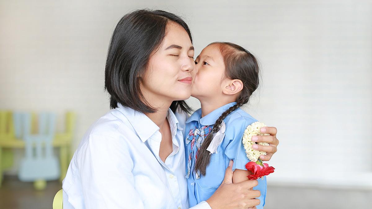 Portrait Asian little girl kissing her mom and hugging on Mother