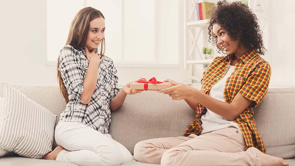 Happy girls exchanging gifts. Excited woman getting present from her friend. Birthday, holidays, celebration and female friendship concept, copy space