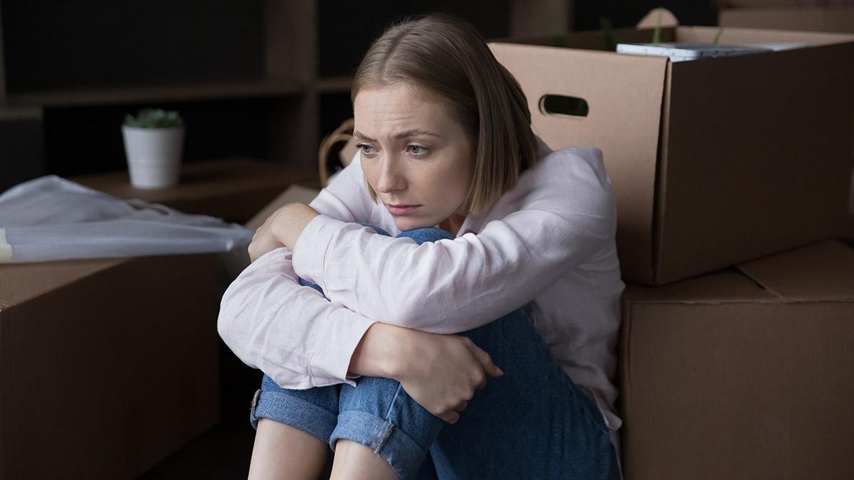 Sad woman sit near heap of cardboard boxes with belongings