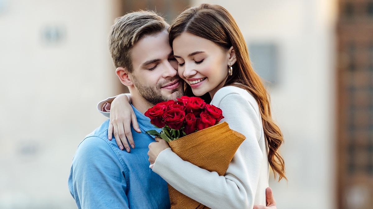 panoramic shot of woman embracing boyfriend while holding bouquet of roses