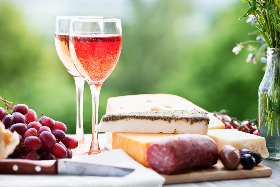 rose wine and cheese with sausage and grapes outdoors