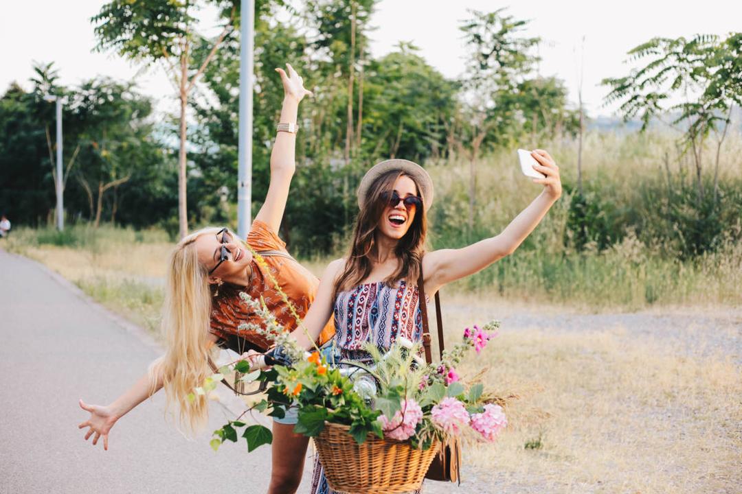 friendship flowers with two best friends riding a bike with flowers in the basket taking a selfie