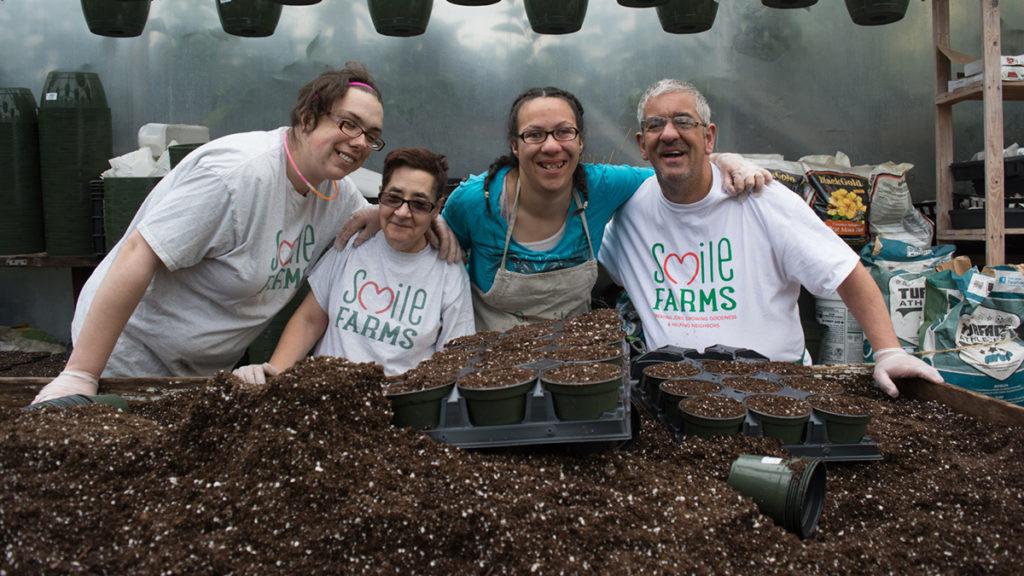 Farmers at Smile Farms pose in front of a planting bed