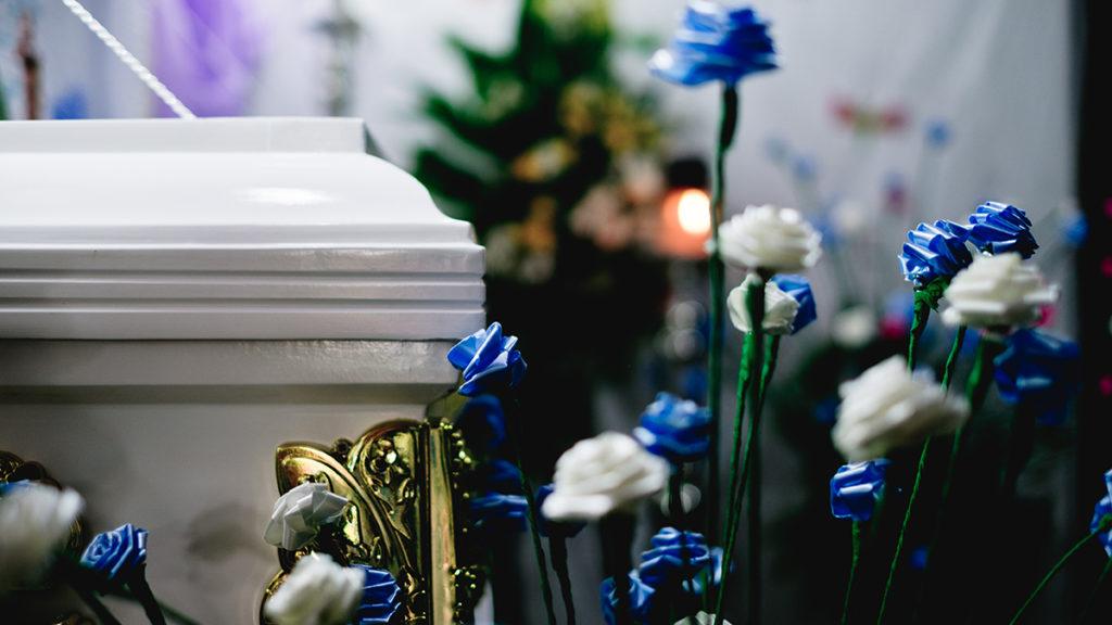 A photo of flowers next to a white casket