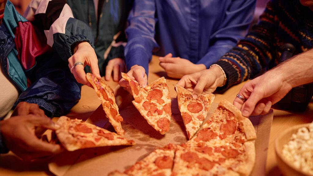 th birthday ideas with Closeup of diverse group of friends sharing pepperoni pizza at house party