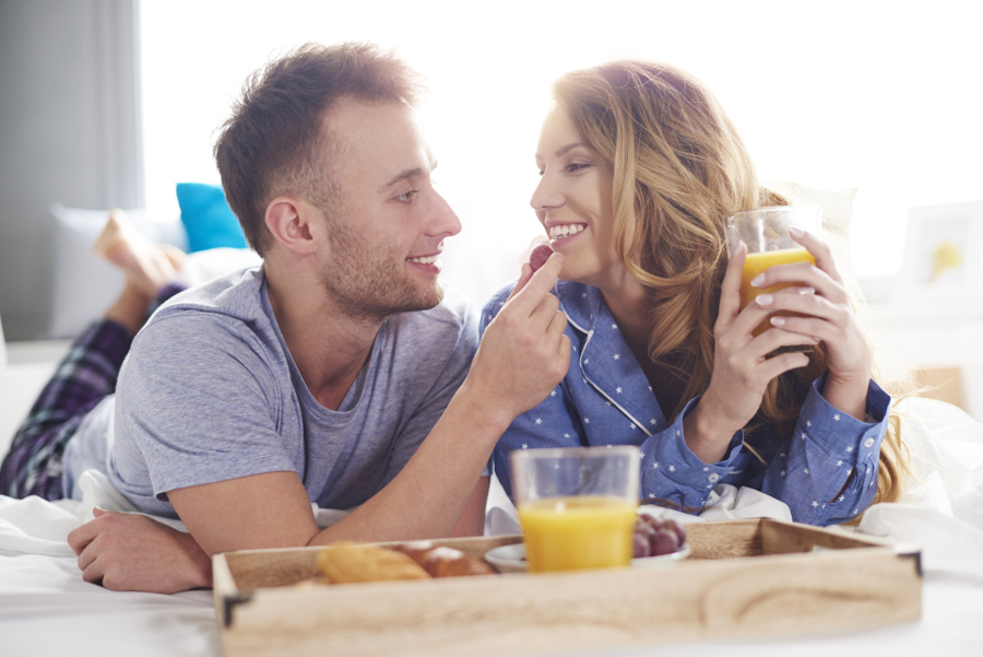 Rainy day date ideas with a couple enjoying breakfast in bed.