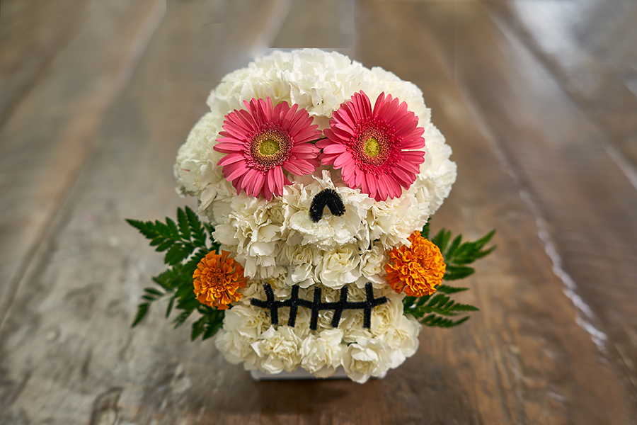 white flower skull with pink flower eyes with marigold flowers