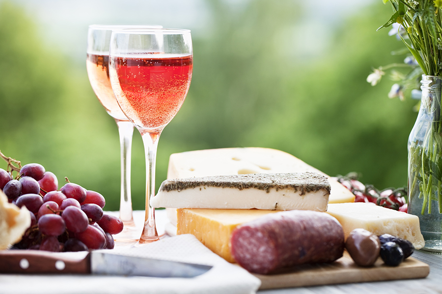 rose wine and cheese with sausage and grapes outdoors