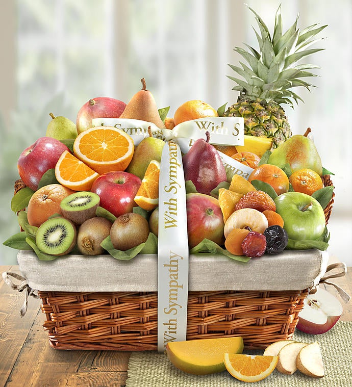 A large basket of fruit with a ribbon wrapped around it that says with sympathy