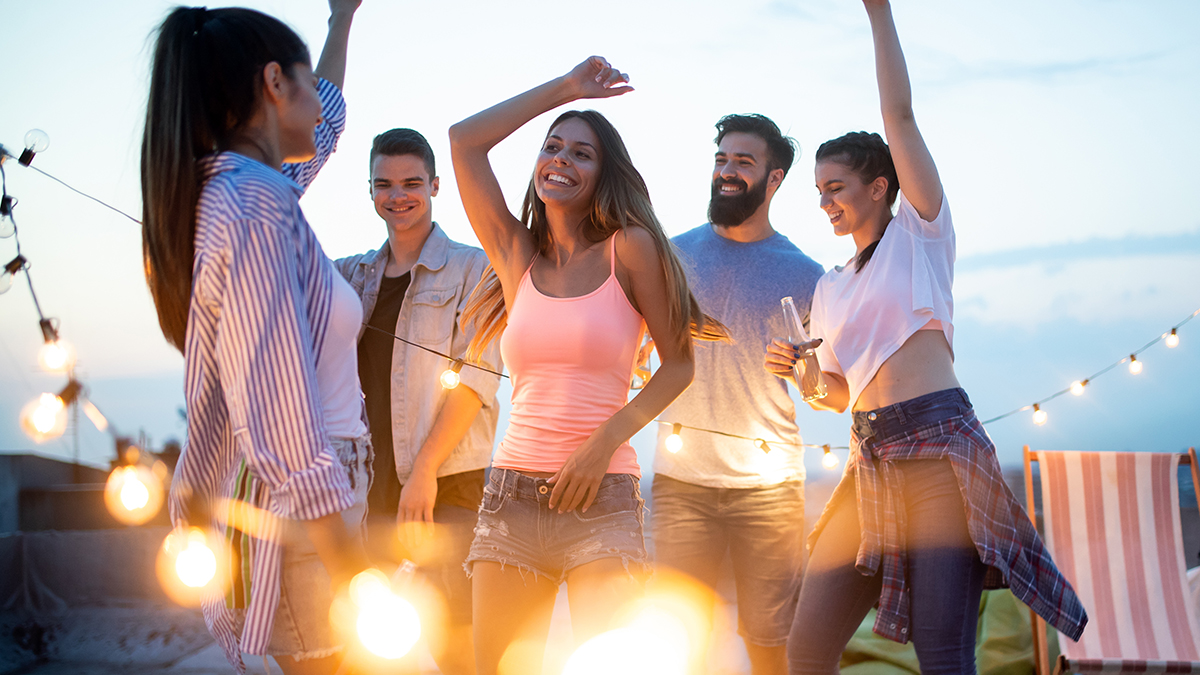 photo of alt bash with friends with drinks toasting at rooftop party at night