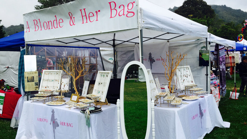 A blonde and her bag with a blonde and her bag booth at a street fair